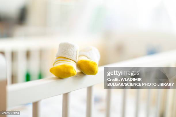 baby booties on the edge of a cot - 赤ちゃんの靴 ストックフォトと画像