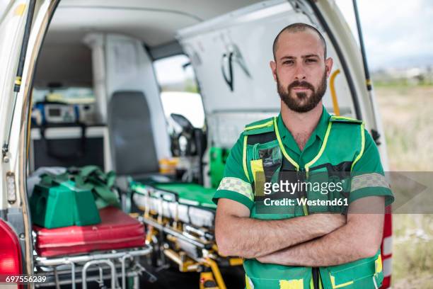 paramedic standing with arms crossed in front of ambulance - rescue worker photos et images de collection