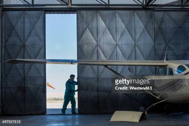 mechanic opening hangar gate - flugzeug hangar stock-fotos und bilder