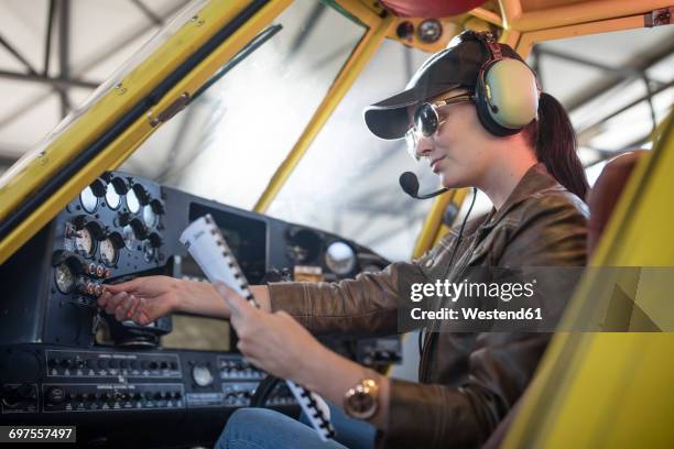 female pilot inspecting light aircraft cockpit - pilot jacket stock-fotos und bilder