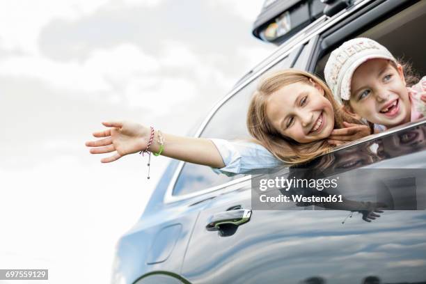 girls sitting in car, looking out of window - happy family car stock-fotos und bilder