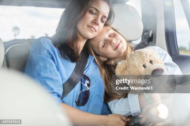 mother and daughter on road trip sitting in car, sleeping - fastening stock-fotos und bilder