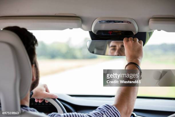 mid adult man driving in car - adjusting stockfoto's en -beelden