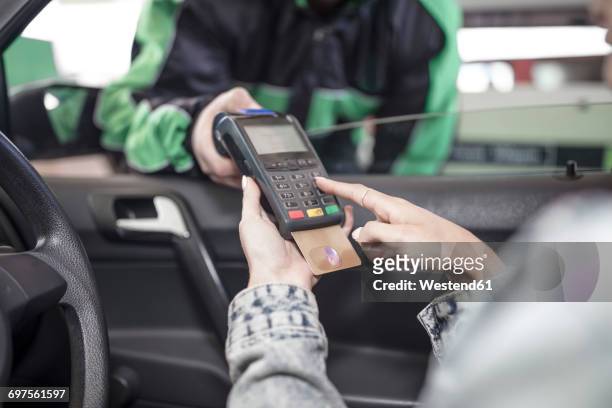 female customer paying with credit card at the fuel station - carte bancaire voiture photos et images de collection