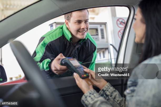 female customer paying with credit card at the fuel station - gas station attendant stock pictures, royalty-free photos & images
