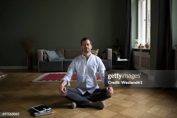 man meditating on the floor at home - ausgeglichenheit stock-fotos und bilder