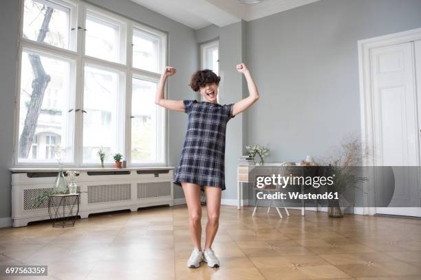 funny young woman flexing her muscles at home - champions portrait stock-fotos und bilder