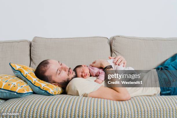 father and his newborn daughter sleeping on the couch - lying on back girl on the sofa stock pictures, royalty-free photos & images