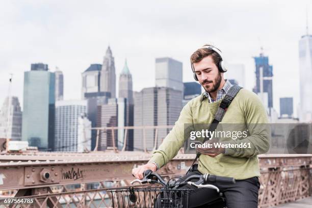 usa, new york city, man on bicycle on brooklyn bridge using cell phone - ragazzo new york foto e immagini stock