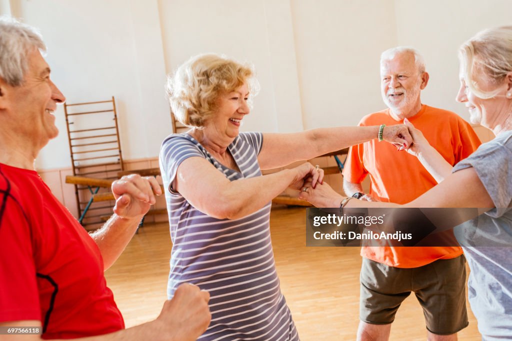 Cheerful group of seniors practice dancing together and having fun