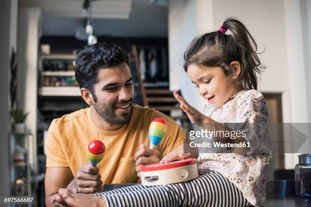 father and daughter playing music in kitchen - toddler musical instrument stock pictures, royalty-free photos & images