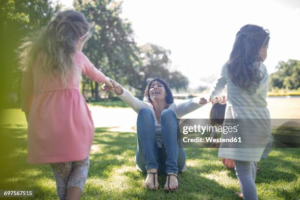 two girls playing with their momther in park - 手を引く ストックフォトと画像