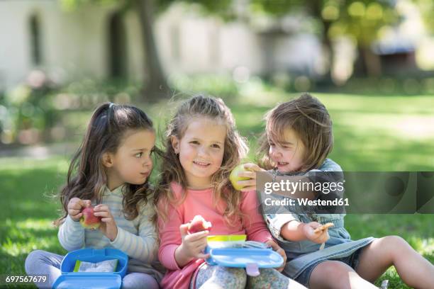 girls in garden sharing lunch - lunch box stock pictures, royalty-free photos & images