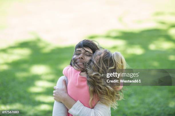mother hugging daughter in garden - cheveux longs photos et images de collection