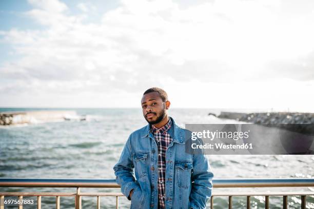 portrait of young man in front of the sea - suspicion stock-fotos und bilder