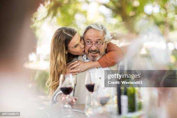 adult daughter embracing father during lunch in garden - old man young woman stockfoto's en -beelden