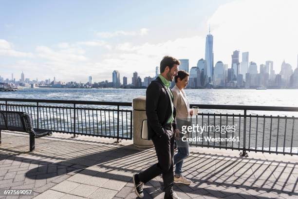 usa, man and woman walking at new jersey waterfront with view to manhattan - panorama nyc day 2 foto e immagini stock