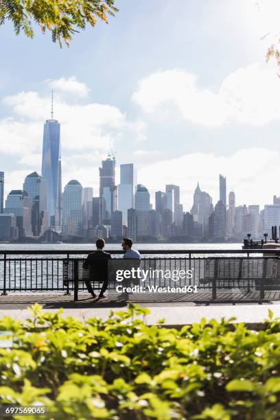 usa, two businessmen sitting on bench at new jersey waterfront with view to manhattan - panorama nyc day 2 foto e immagini stock