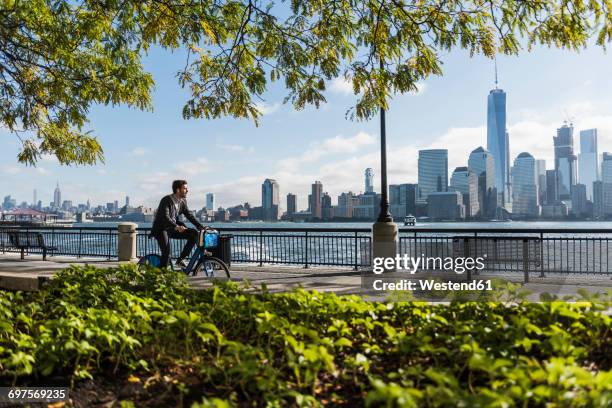 usa, man on bicycle at new jersey waterfront with view to manhattan - hudson river stock pictures, royalty-free photos & images