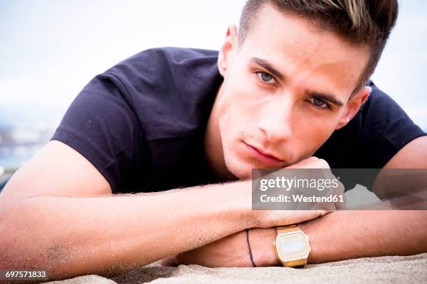 portrait of unhappy young man lying on the beach - lying on front stock pictures, royalty-free photos & images