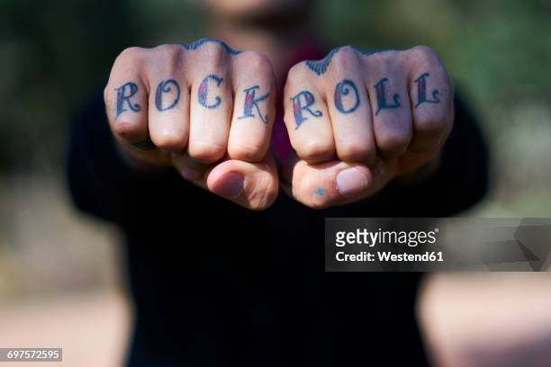 fingers tattooed with 'rock and roll' - hand rock stock pictures, royalty-free photos & images