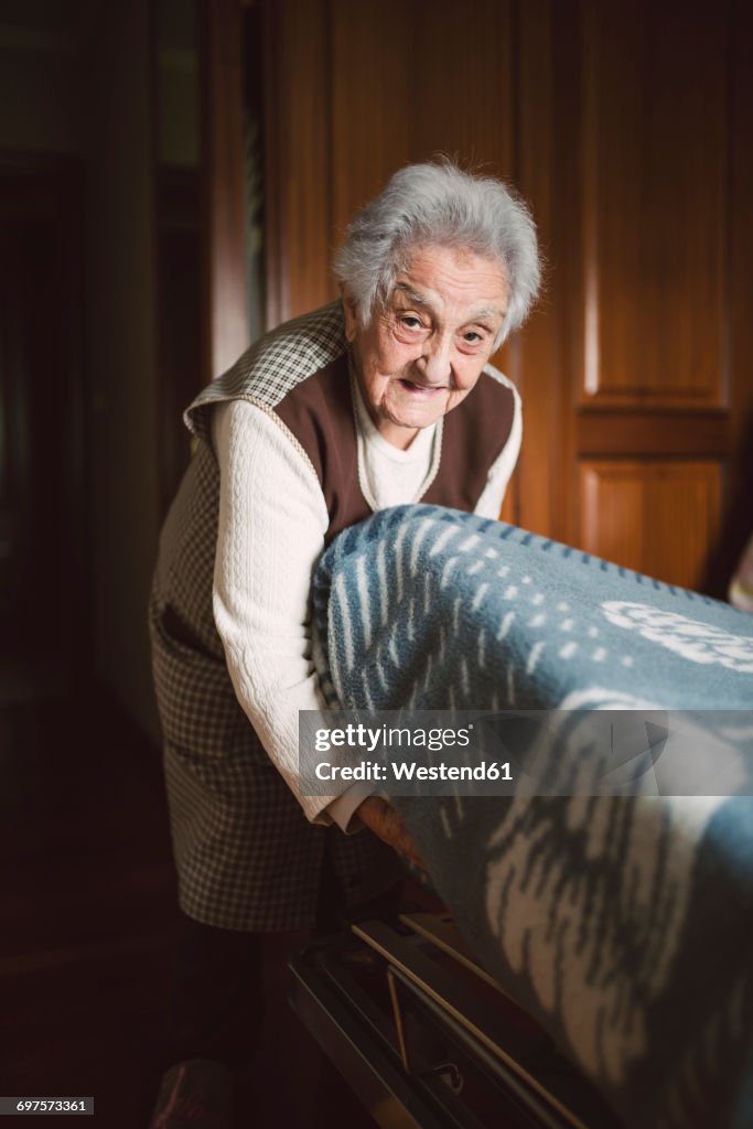 Senior woman putting fresh sheets on a bed