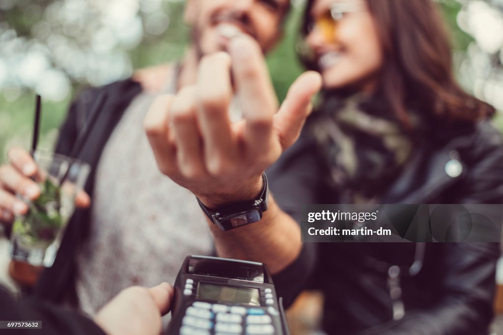 Man på café betala kontaktlöst med smartwatch