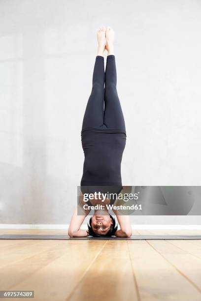 woman practising yoga doing a headstand - inverted stock pictures, royalty-free photos & images