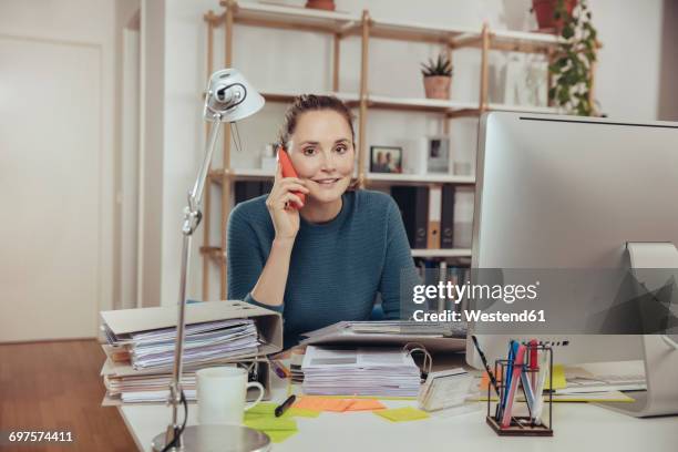 woman talking on the phone in home office - frau aktenordner stock-fotos und bilder