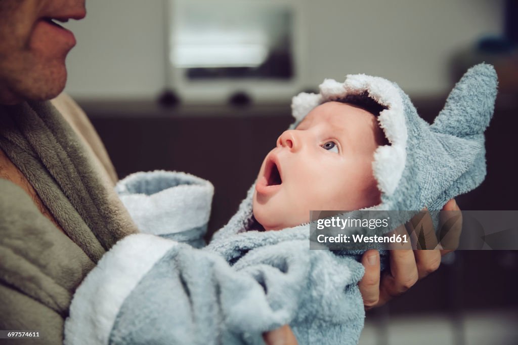 Father holding baby wearing shark bathrobe