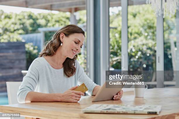 woman sitting on terrace, doing online payment with credit card - mobile banking stock-fotos und bilder