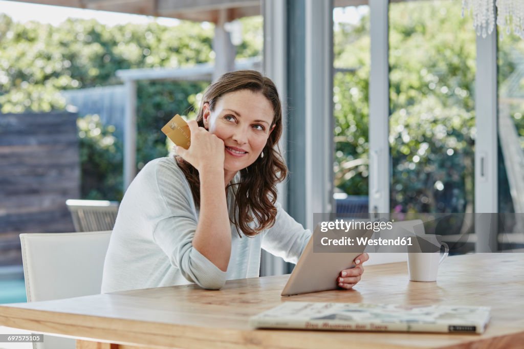 Woman sitting on terrace, doing online payment with credit card