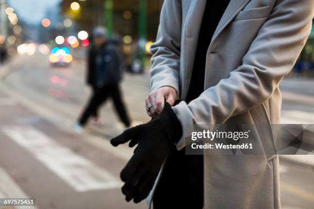 close-up of man in the city putting on gloves - putting gloves stock pictures, royalty-free photos & images