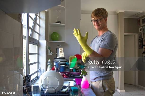 a young man washing a large amount of dishes. - washing up glove - fotografias e filmes do acervo
