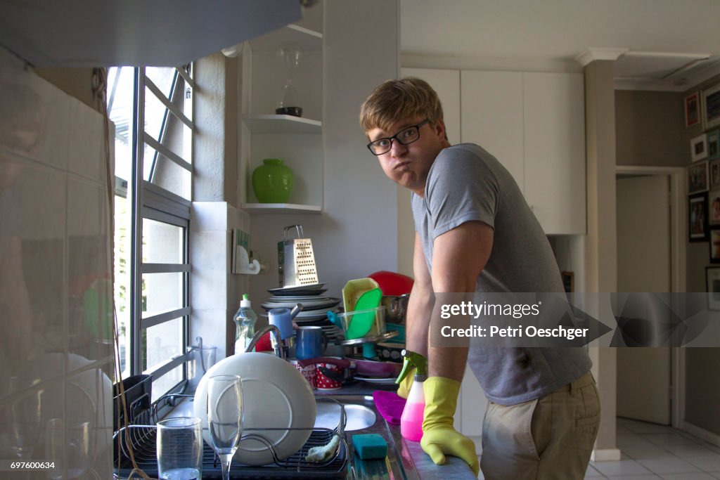 A Young man washing a large amount of dishes.