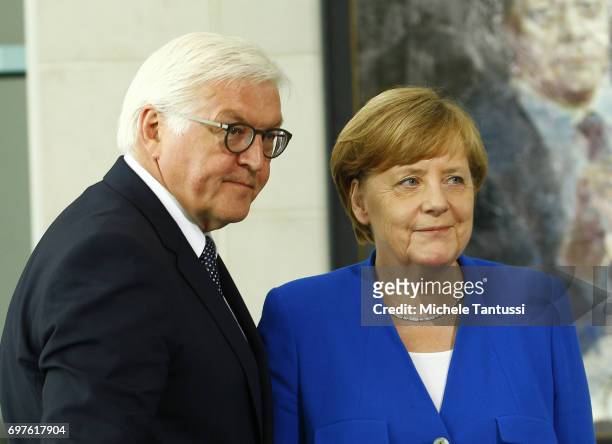 German chancellor Angela Merkel stands by German Federal President Frank-Walter Steinmeier as he signs a book of condolences next to a portrait of...