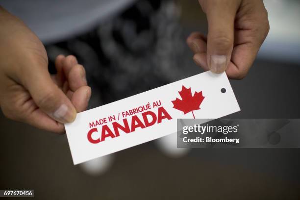 Worker displays a "Made In Canada" clothing tag for a photograph at the WS & Co. Production facility in Toronto, Ontario, Canada, on Friday, June 9,...