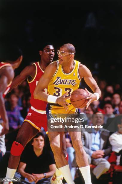 Kareem Abdul-Jabbar of the Los Angeles Lakers handles the ball against Hakeem Olajuwon of the Houston Rockets during a game played circa 1986 at the...