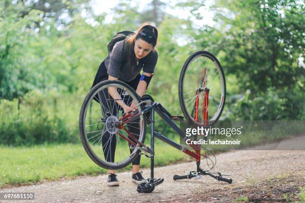 junge frau, die ihr fahrrad reparieren - autoreifen natur stock-fotos und bilder