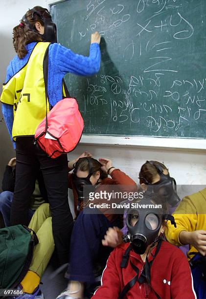 Israeli teenager Coral Henigman catches up on her classwork as she wears a gas mask in a bomb shelter during a civil defense exercise at a school...