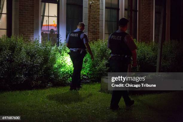 Chicago Police officers search bushes near the scene where a man and woman, both in their 60s, were found stabbed to death in a home by a family...