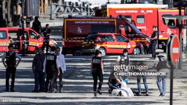 Graphic content / Judiciary Police Officers tend to the body of a suspect lying under a white sheet in a sealed off area of the Champs-Elysees avenue...