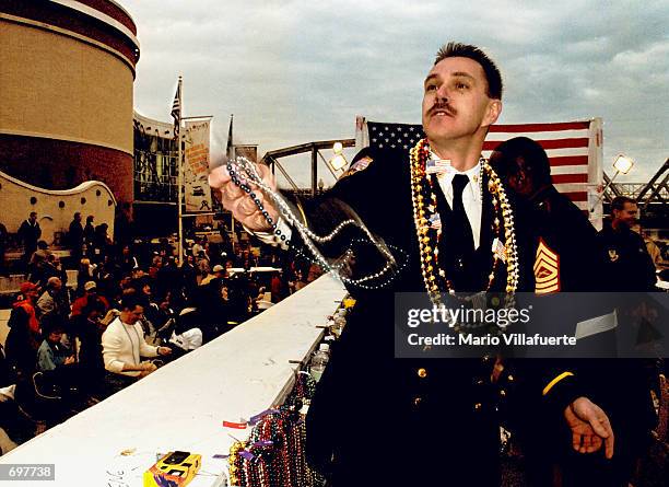 Gene Vellia, Battalion Chief with the Fire Department of New York, flings beads into the crowd February 2, 2002 during the" Krewe of Centura" Mardi...