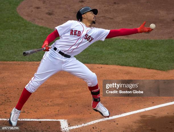 Red Sox player Mookie Betts shows off his multi-talents by catching a ball that ricocheted back on the field in the batter's box at Fenway Park in...