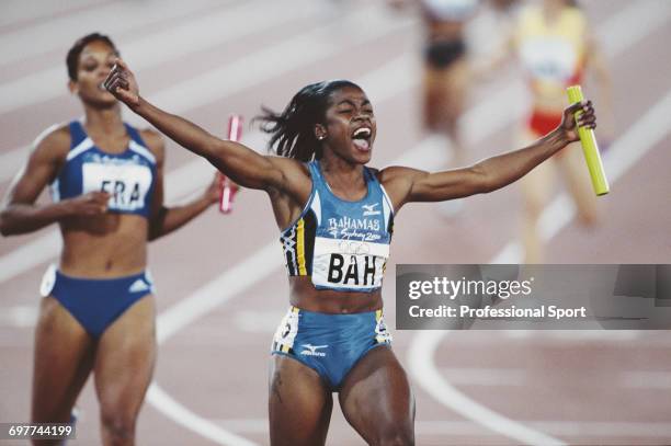 Bahamian track athlete Debbie Ferguson-McKenzie raises her arms in the air in celebration as she crosses the finish line in first place for the...