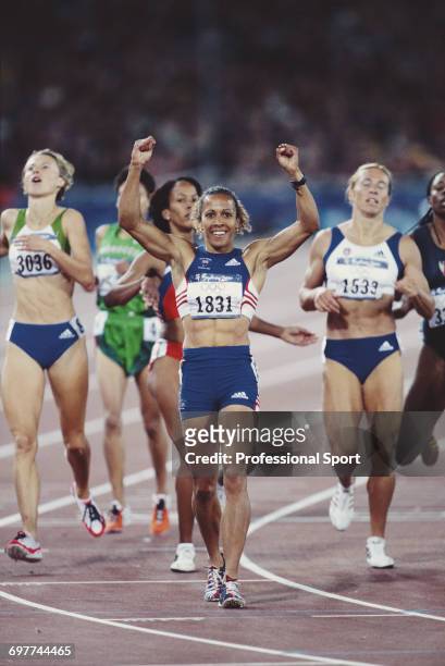 English track athlete Kelly Holmes raises her arms in the air in celebration as she crosses the finish line in third place for the Great Britain team...