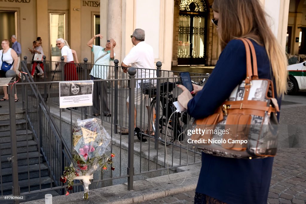 A person takes a photo of a sign and flowers in memory of...