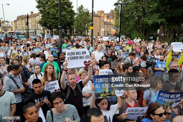 People hold up signs saying 'united against terror' as they attend a vigil outside Finsbury Park Mosque on June 19, 2017 in London, England....