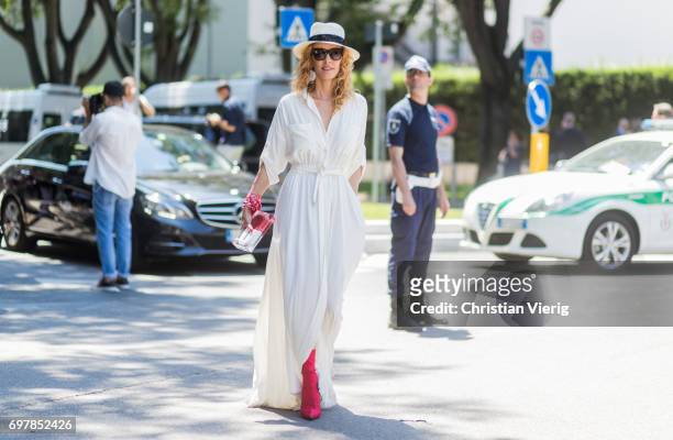 Elina Halimi wearing a white dress, straw hat, red boots is seen outside Armani during Milan Men's Fashion Week Spring/Summer 2018 on June 19, 2017...