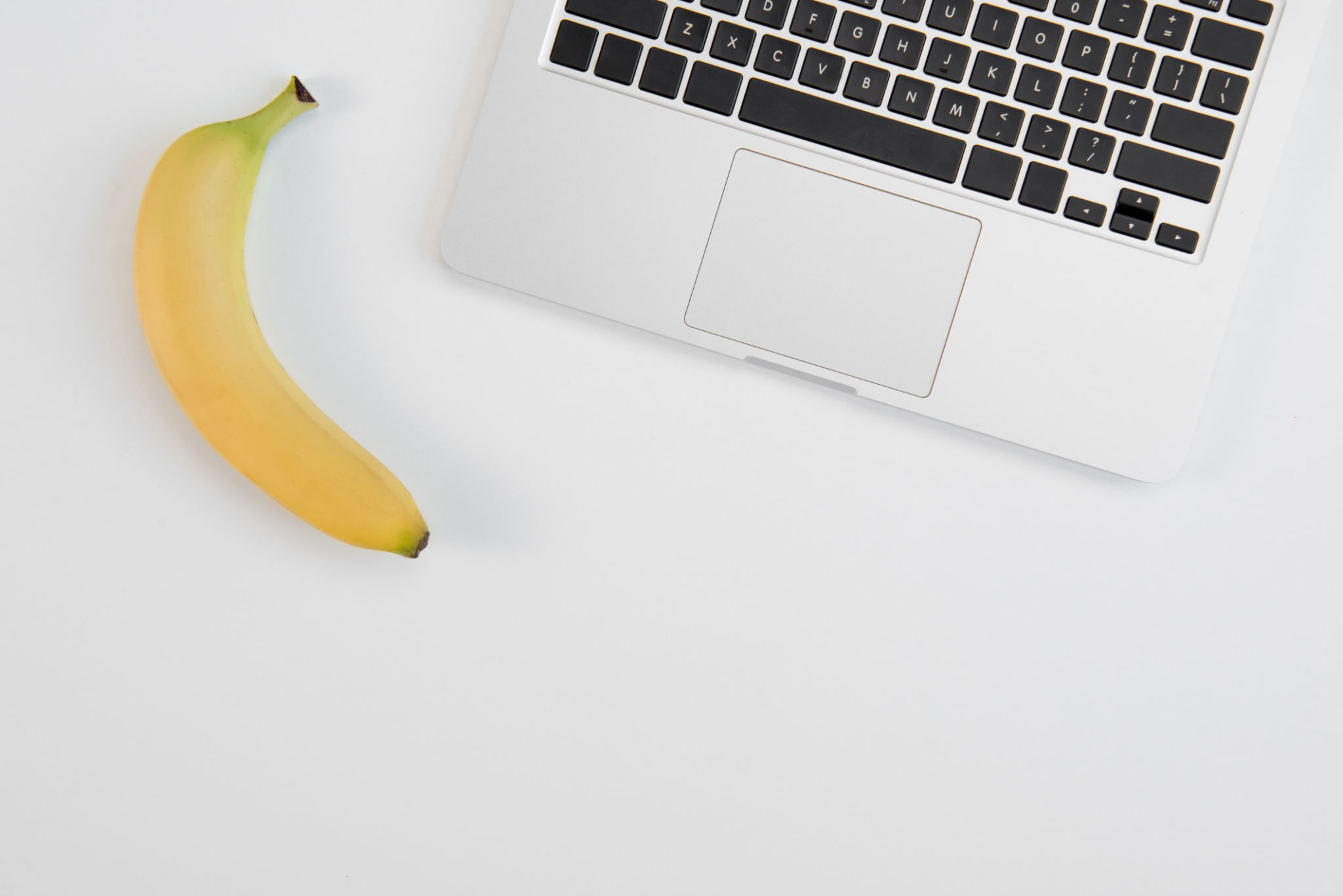 Top view of laptop and fresh ripe banana isolated on grey background Top view of laptop and fresh ripe banana isolated on grey background